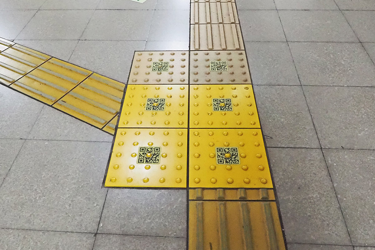 写真：駅構内の点字ブロック上のQRコード（shikAI）